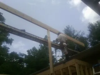 Carpenter setting a ridge beam over a new addition frame — Ice Dam Removal by Roofing Brothers in Hosford