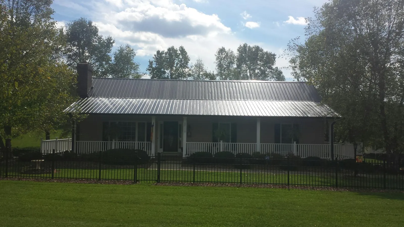 Gray metal roof on a brick ranch with a full width front porch — Gutter Guard Installation work by our crew in Hosford
