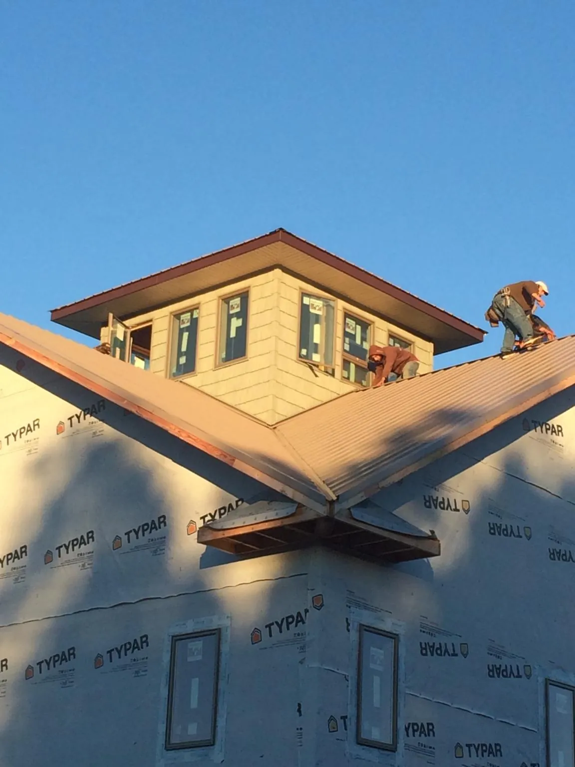 Roofers working around a rooftop cupola on a new metal roof at sunset — Roof Waterproofing in Hosford by Roofing Brothers